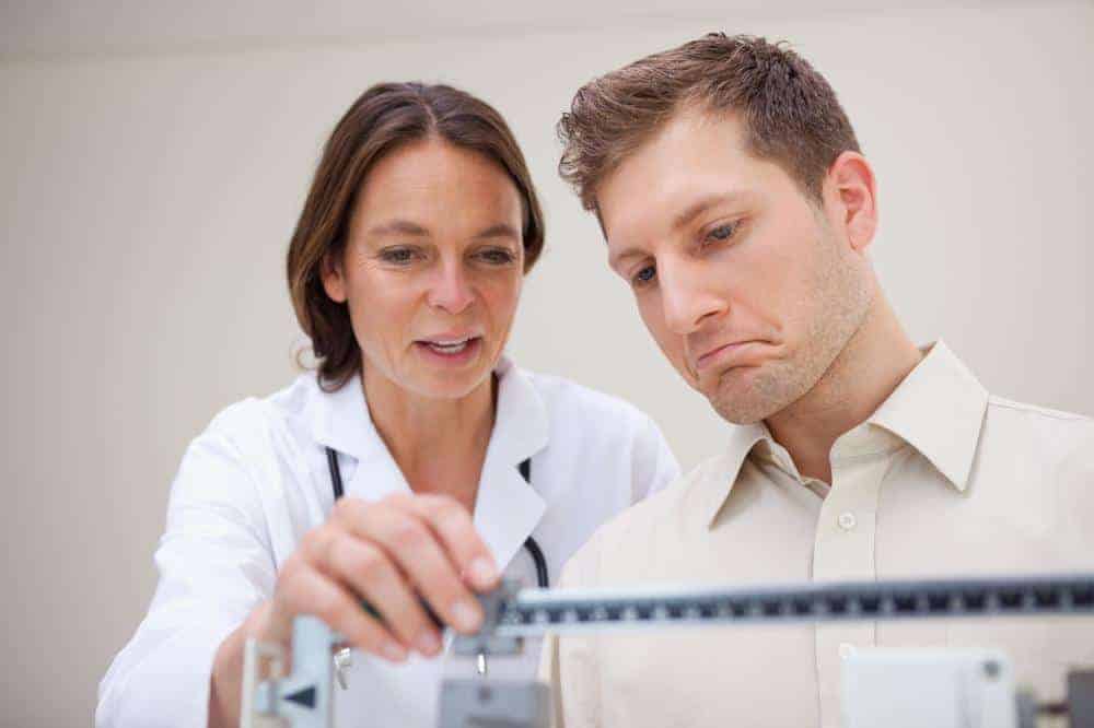 man getting weighed for health purposes