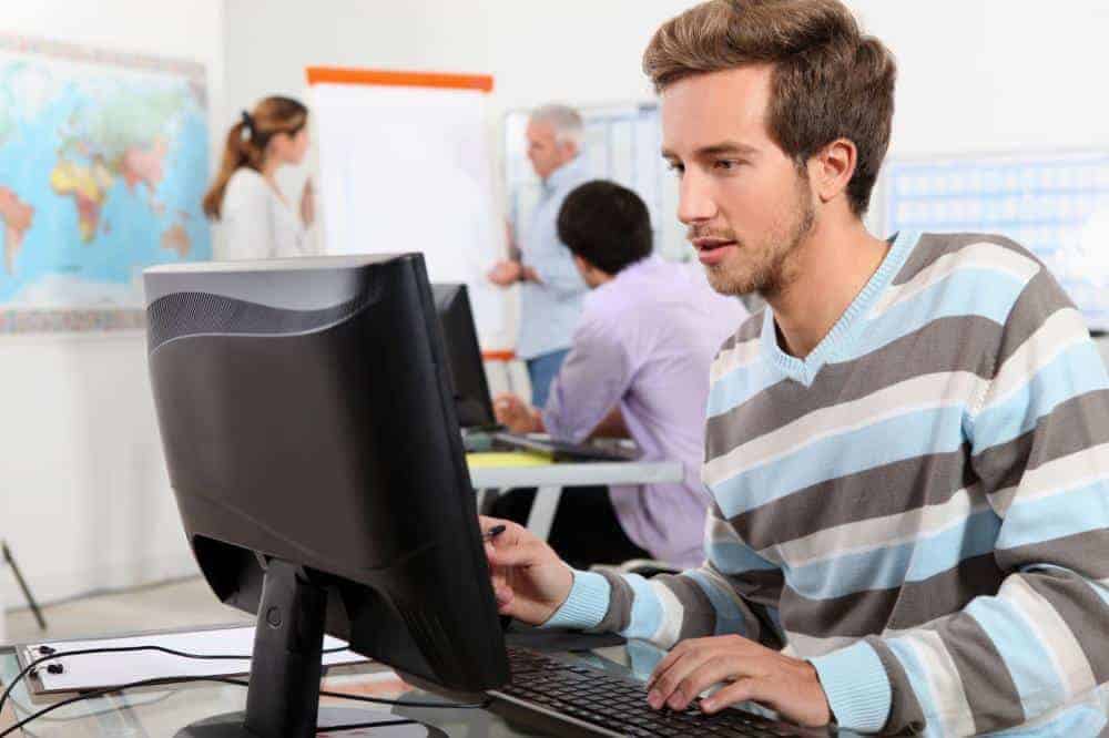 young man at work on his computer with people in the background