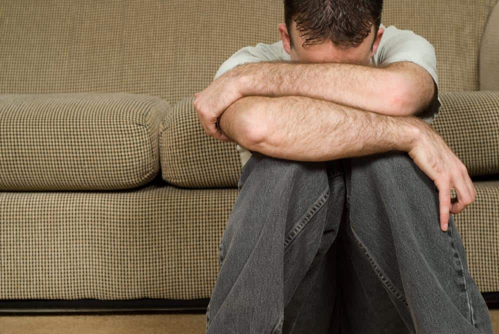 depressed man sitting on the floor near couch
