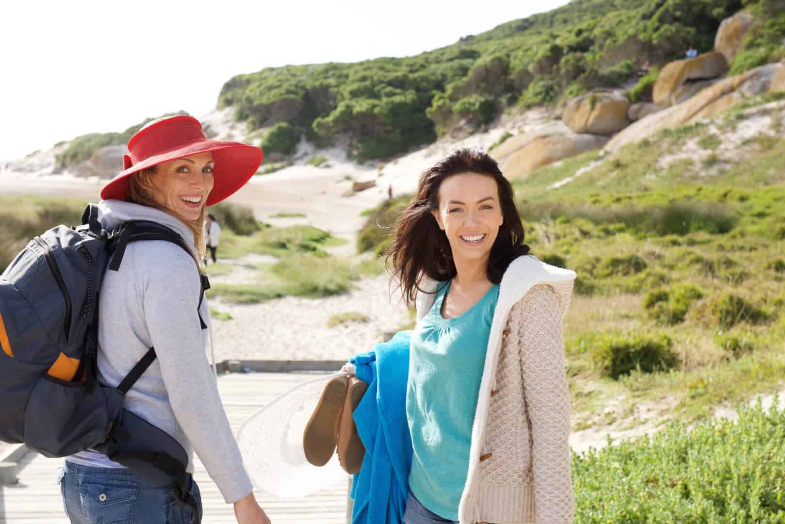 two-women-friends-walking-to-the-beach-with-bag