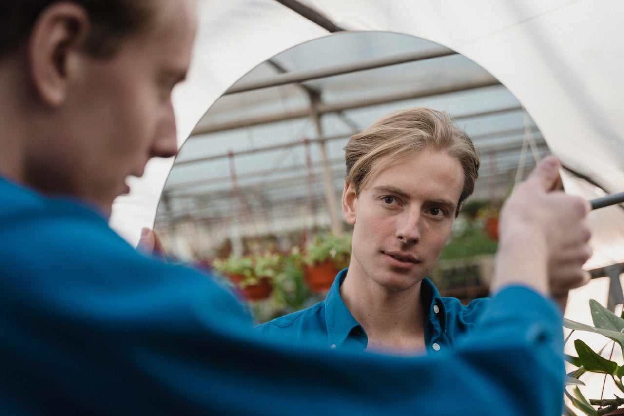 man looking in mirror thinking forgiveness